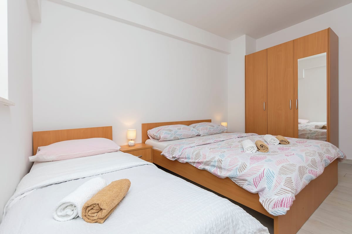 A hotel room with a wooden bed, white linens, a nightstand with a lamp, and a wardrobe.