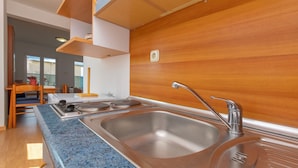 A modern kitchen with a granite countertop, stainless steel sink, and wooden cabinetry. - Apartments Villa Milas With Pool (Jesenice)