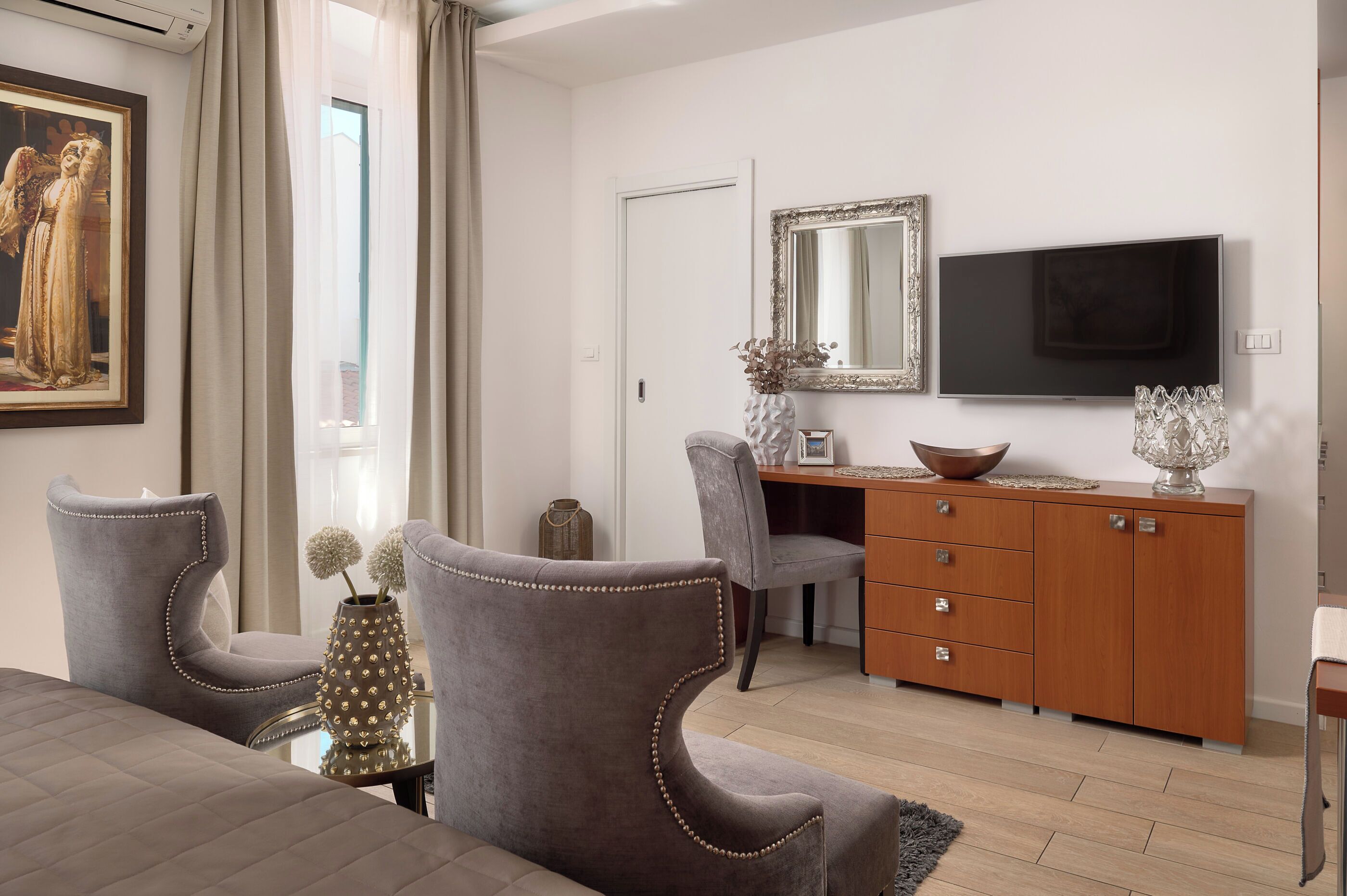 Una sala de estar moderna con un sofá, dos sillones, un aparador de madera, un televisor y un espejo grande.