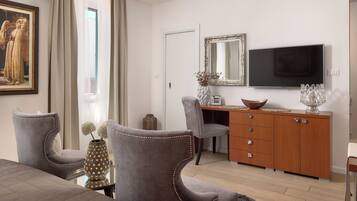 Una sala de estar moderna con un sofá, dos sillones, un aparador de madera, un televisor y un espejo grande.
