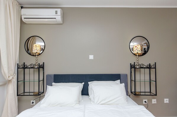 A hotel room with a bed, two bedside tables with lamps, an air conditioner, and a mirror on the wall. - Apartments Urban (Split)