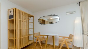 Una habitación con una cuna de madera, un espejo redondo y una pequeña mesa con dos sillas.