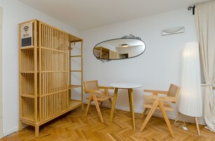 Une pièce avec un berceau en bois, un miroir rond et une petite table avec deux chaises.