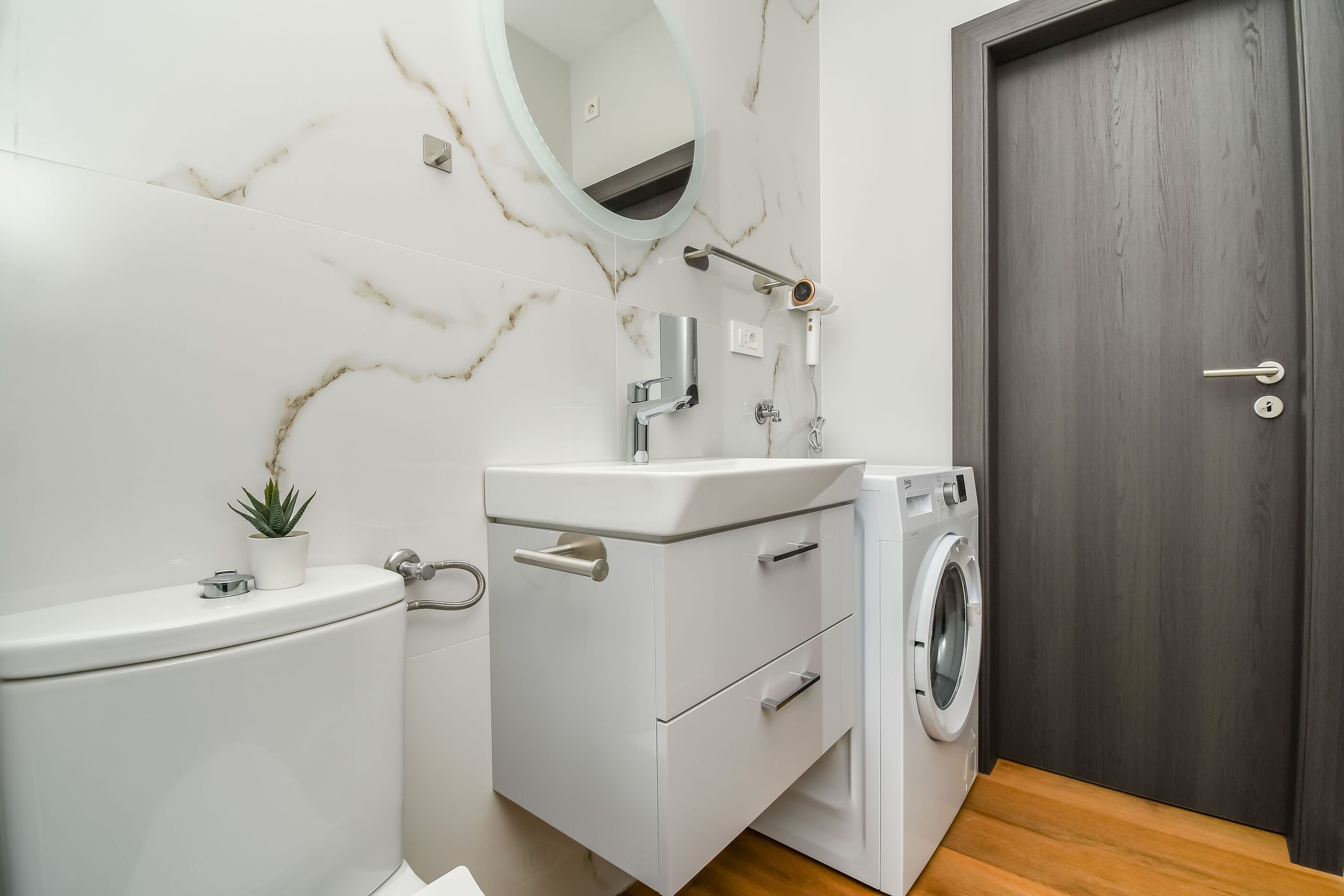 A modern bathroom with a toilet, sink, and washing machine.