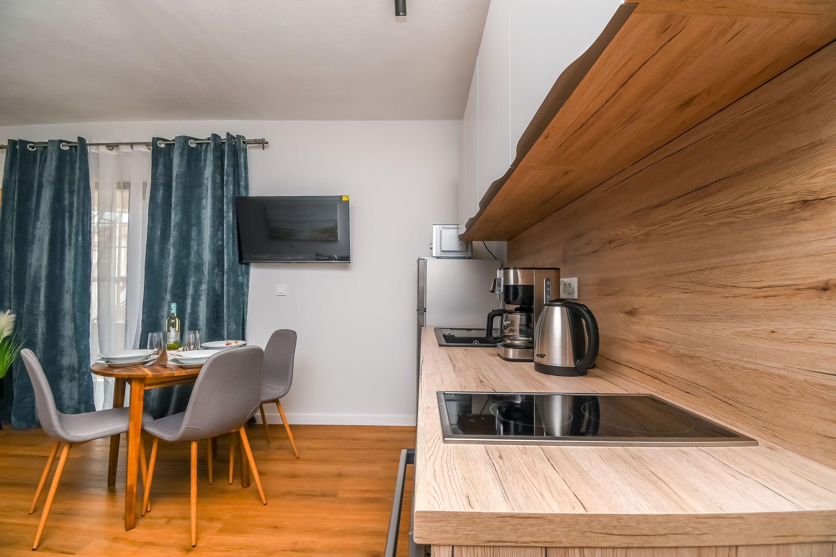 A modern kitchen with a wooden countertop, a built-in stove, and a coffee maker.