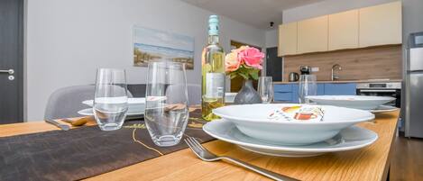 Une table à manger dressée avec des assiettes, des verres, une bouteille et un vase rempli de fleurs.