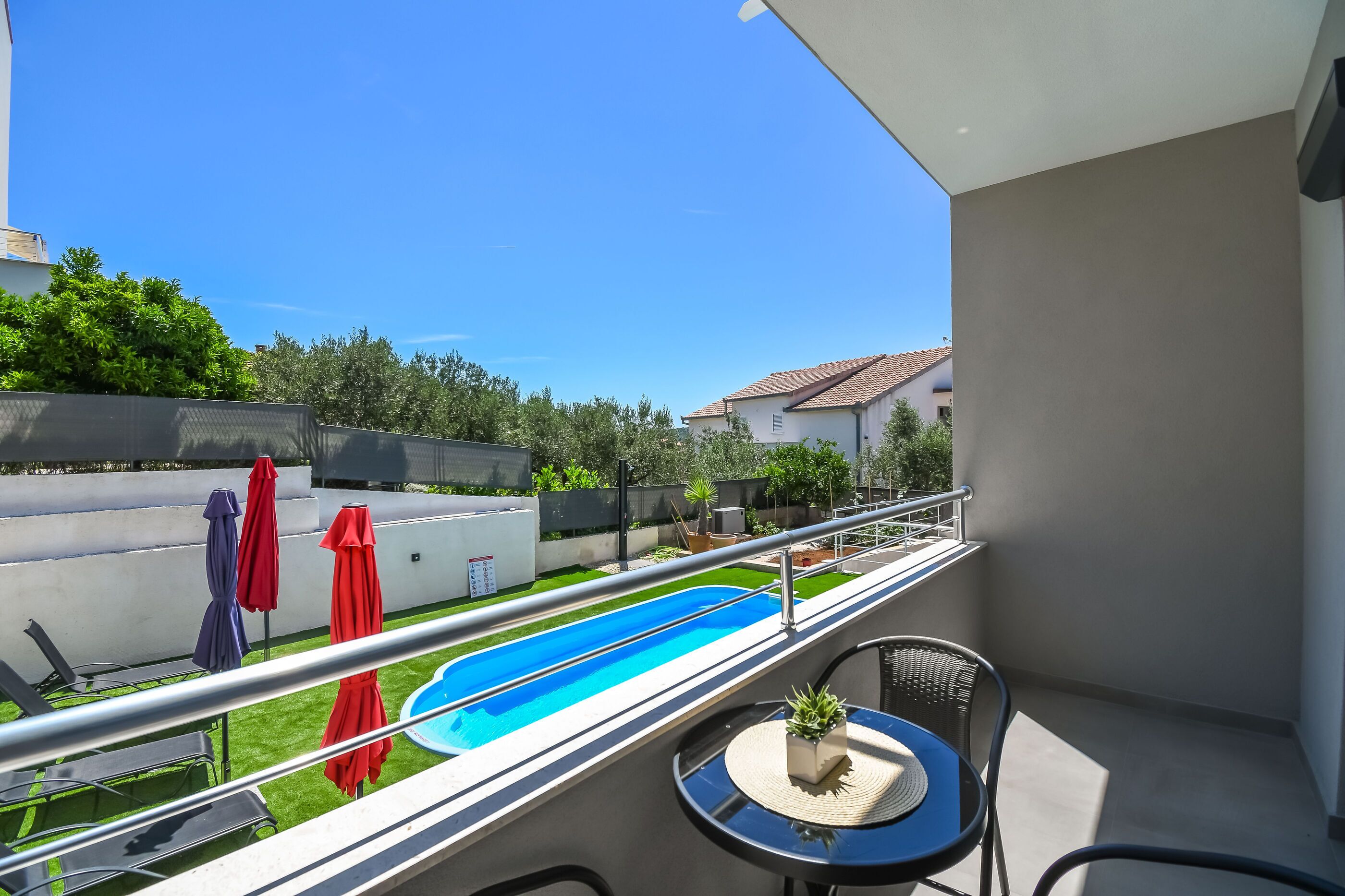 A balcony with a pool, outdoor furniture, and umbrellas.