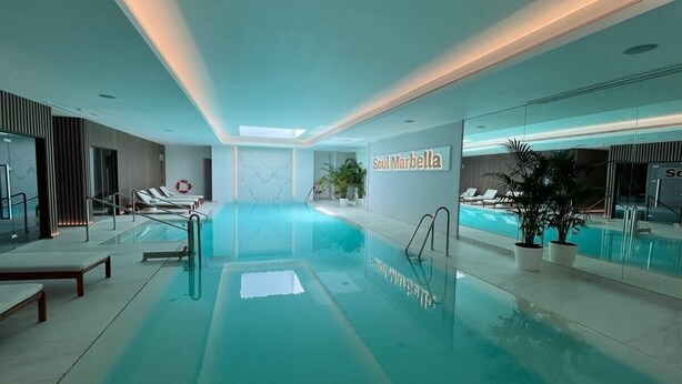 An indoor swimming pool with lounge chairs and a sign reading "Soul Marbella".