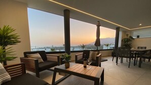 A modern outdoor seating area with sofas, a table, and chairs, overlooking a scenic view.