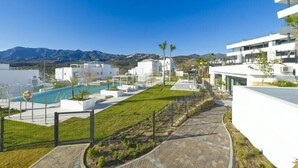 A modern hotel with a swimming pool, a well-maintained lawn, and a view of mountains.