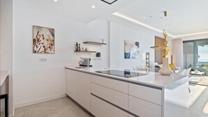 A modern kitchen with a central island, white cabinetry, and minimalist decor.