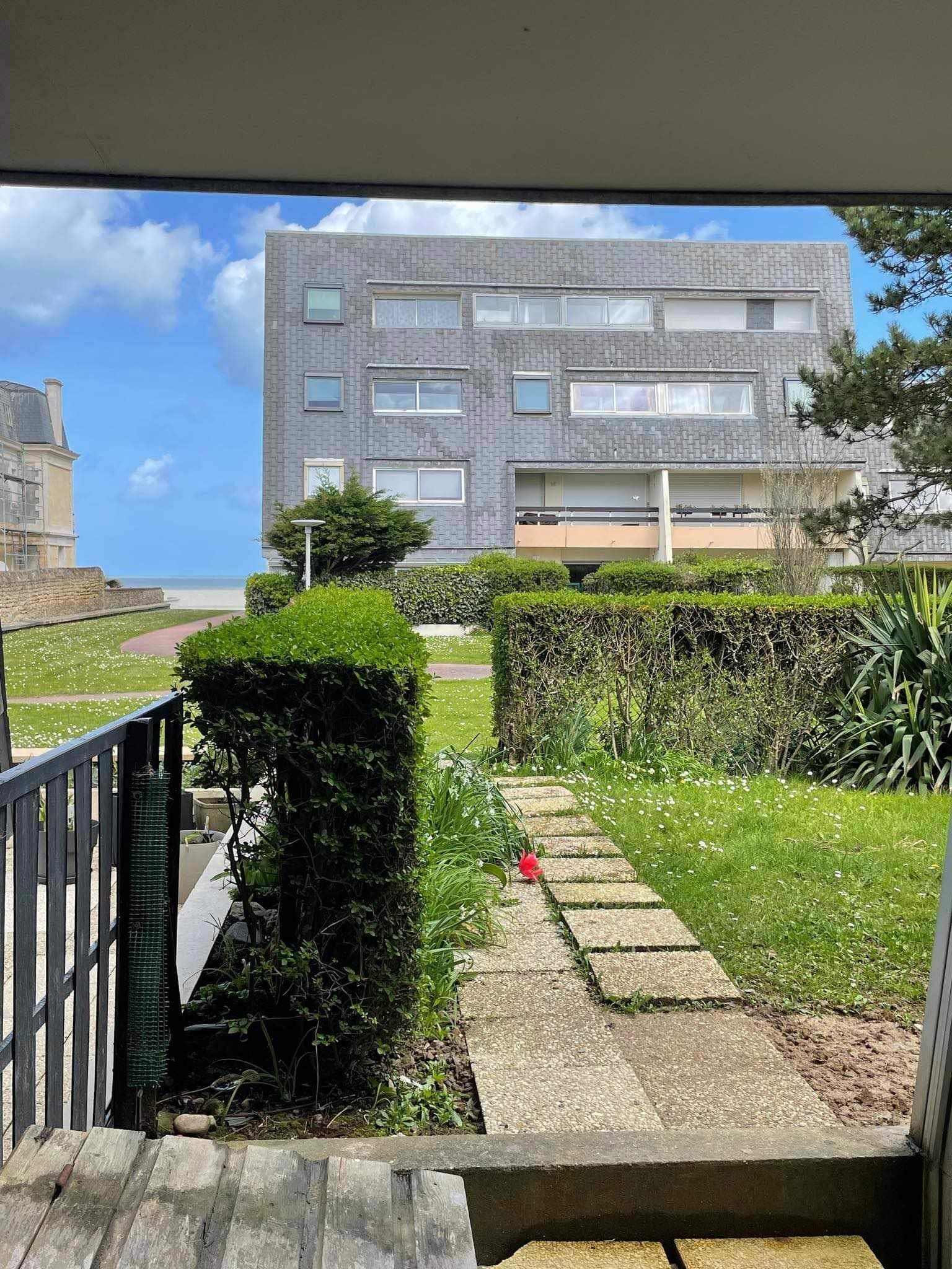 Un edificio residencial con fachada de ladrillo, un camino que lleva a una entrada con portón y vista al mar de fondo.