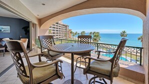 Un balcon avec une table ronde et quatre chaises, offrant une vue sur la piscine et l’océan.