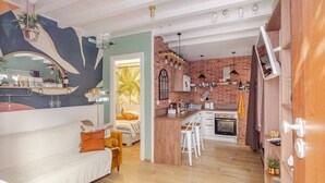 A modern living room with a sofa, a dining area with stools, and a kitchen with brick walls and a wooden counter. - Vita Lenta Pigneto: your apartment with terrace and jacuzzi in the heart of Rome (Roma)