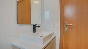 A bathroom with a white sink, a mirror, and a wooden door.