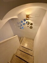 Una escalera moderna con un diseño circular único en la pared, una lámpara y un suelo con textura.