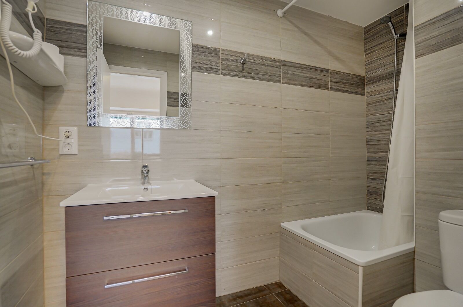 Une salle de bain moderne avec un lavabo blanc, un meuble-lavabo en bois et une baignoire.