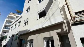 Un edificio de varios pisos con fachada plana, varias ventanas y una puerta visible.