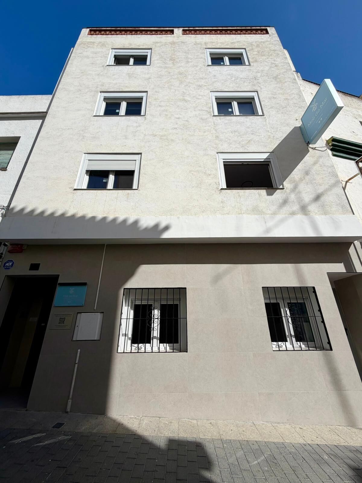 Um edifício com vários andares, fachada plana, diversas janelas e entrada visível.