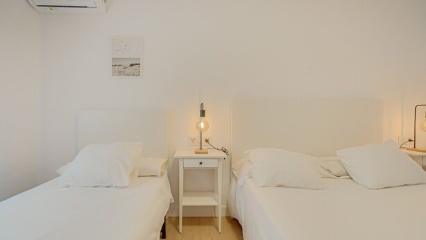 Une chambre d’hôtel avec deux lits simples, une table de chevet avec une lampe et un climatiseur fixé au mur.