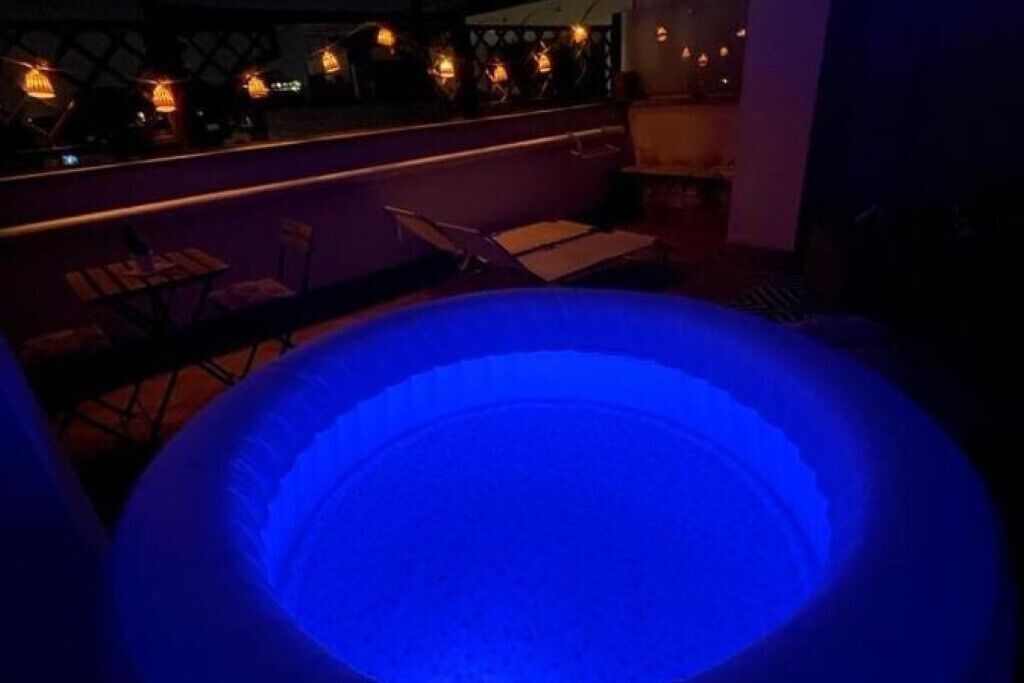 Una vasca idromassaggio in una stanza scarsamente illuminata, con un bar e un angolo salotto.