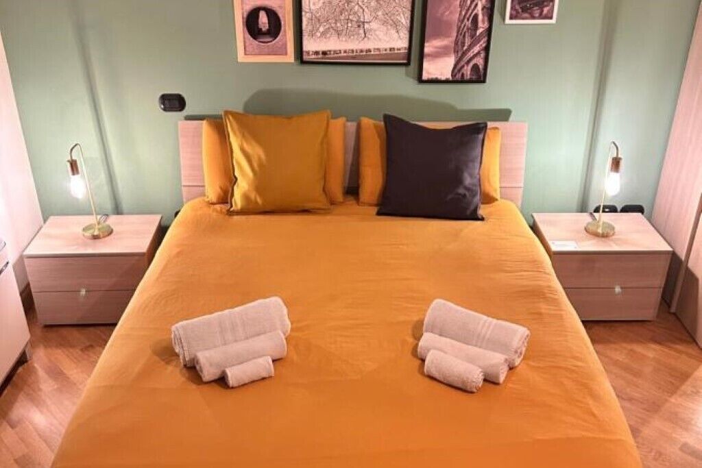 A hotel room with a large bed, two nightstands, and a wall with framed pictures.