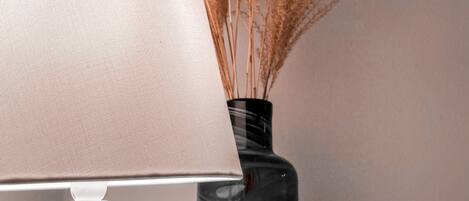 Eine Lampe mit beigeem Lampenschirm und eine Vase mit getrocknetem Pampasgras.