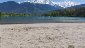 A lake with mountains in the background and a sandy beach in the foreground.