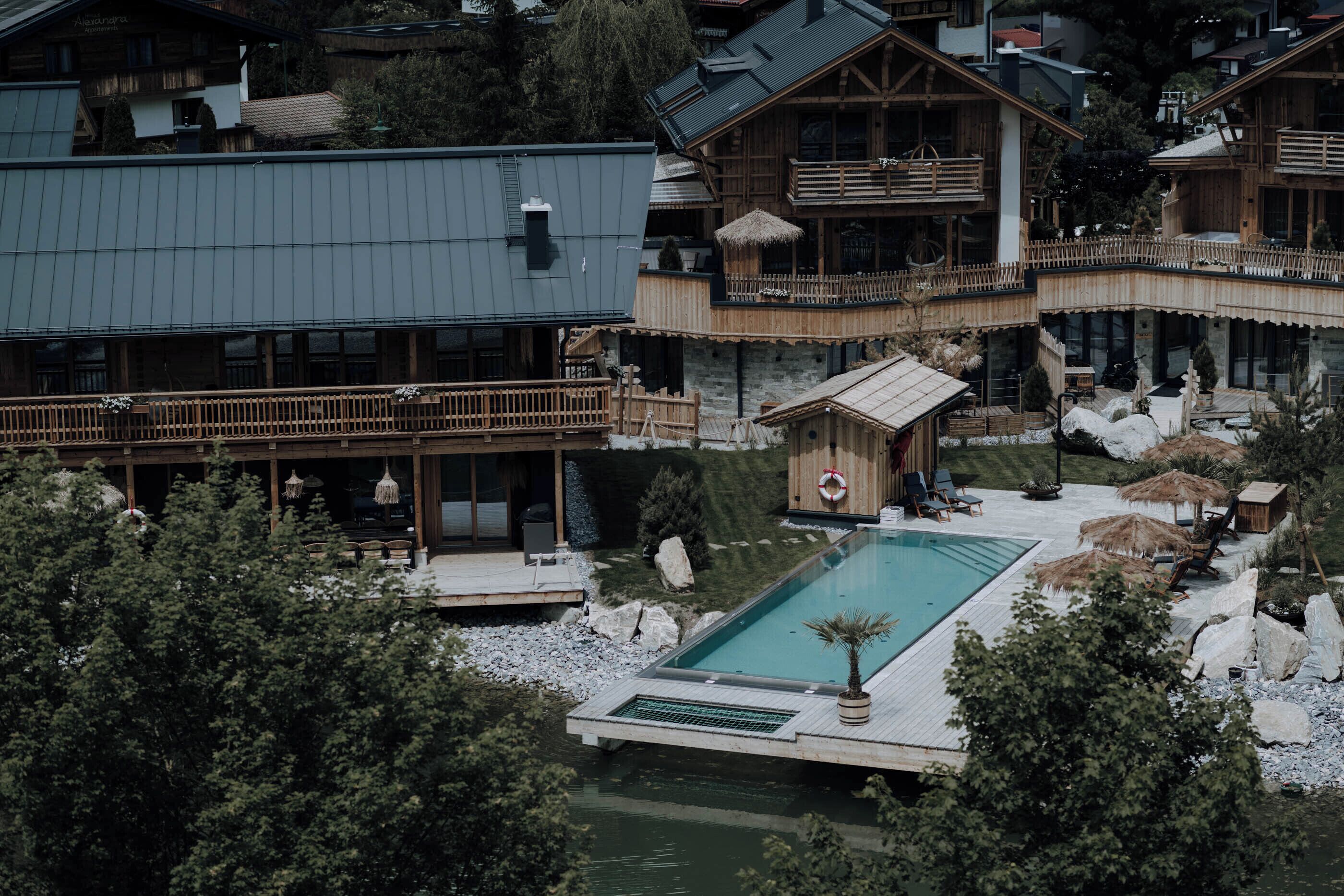 Et resort med swimmingpool, træterrasse og flere balkoner.