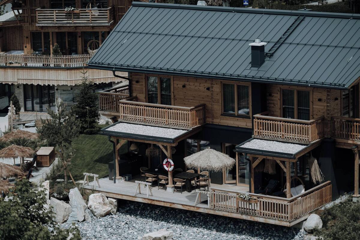 Una cabaña de madera con varios balcones, mobiliario exterior y una terraza.