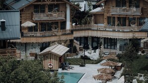 Un chalet en bois doté d’une piscine, de chaises longues et de parasols.
