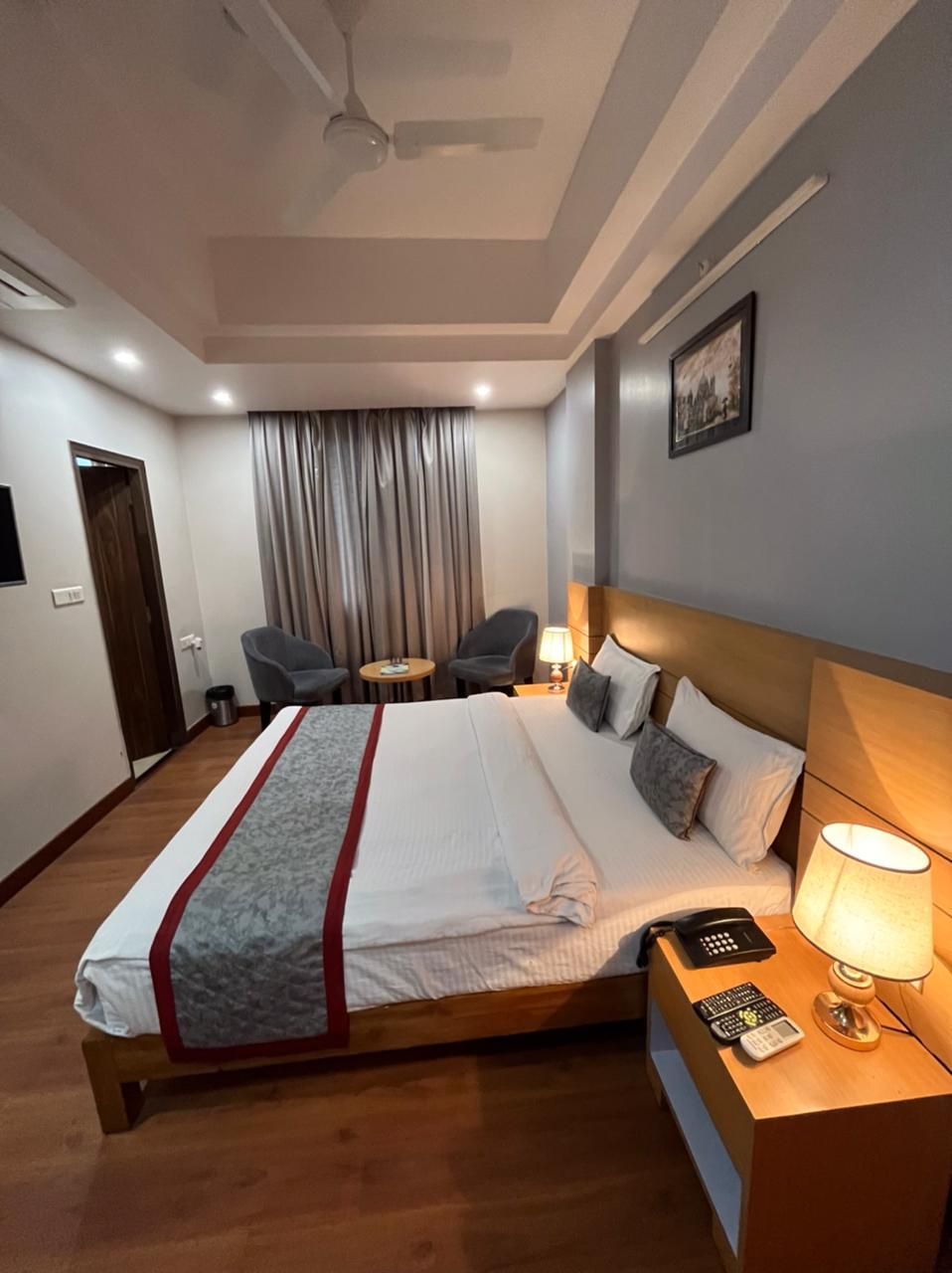 Une chambre d’hôtel avec un lit, une table de chevet, une lampe et une chaise.