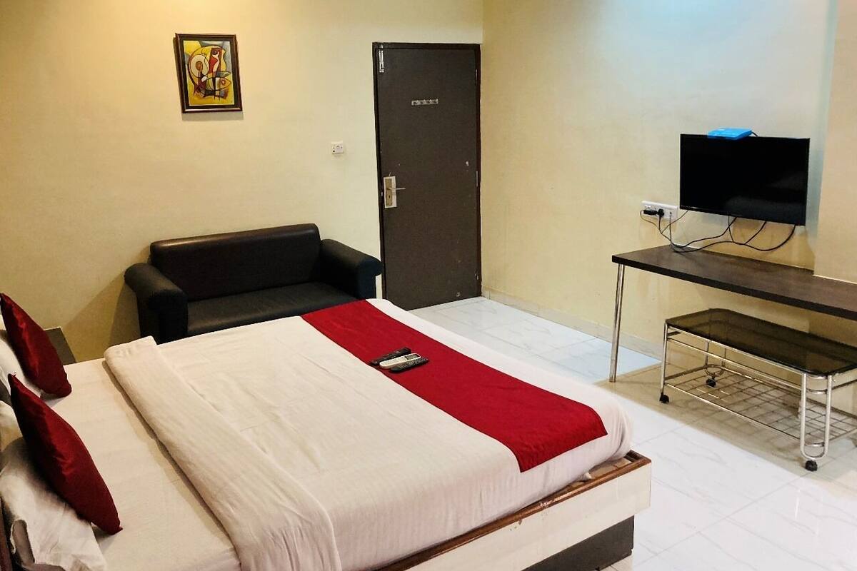 Una habitación de hotel con una cama, un escritorio con televisor, una silla y una puerta.