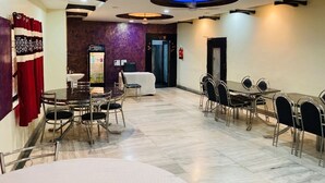 Un comedor amplio con una mesa central y sillas, un mostrador de recepción y una pared de acento morada.