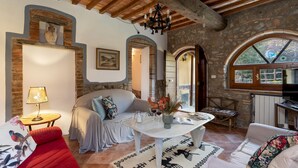 A cozy living room with a sofa, a table with a vase, and a television. - Il Pratone 12 Emma Villas (Pomarance)