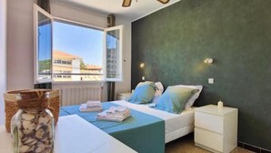 Ein Schlafzimmer mit Bett, Nachttisch, Fenster mit Blick und einem dekorativen Korb.