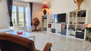Ein Wohnzimmer mit einer Couch, einem Couchtisch, einem Fernseher und einem Bücherregal.