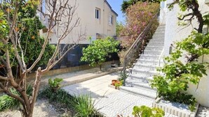 Ein Innenhof mit einer Treppe, die zu einem Gebäude führt, umgeben von Grünpflanzen und einem Steinweg.