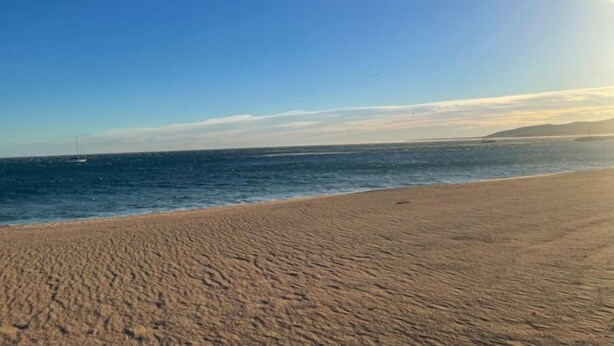 Ein Strand mit blauem Himmel und ruhiger See.