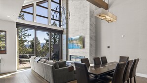 A spacious living area with a large dining table, comfortable seating, and a large window offering a scenic view. - 305A Boulder | 4BR/4BA Crystal Bay Lake View (Crystal Bay)
