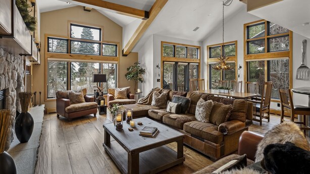 A spacious living room with a high ceiling, large windows, and a cozy fireplace.