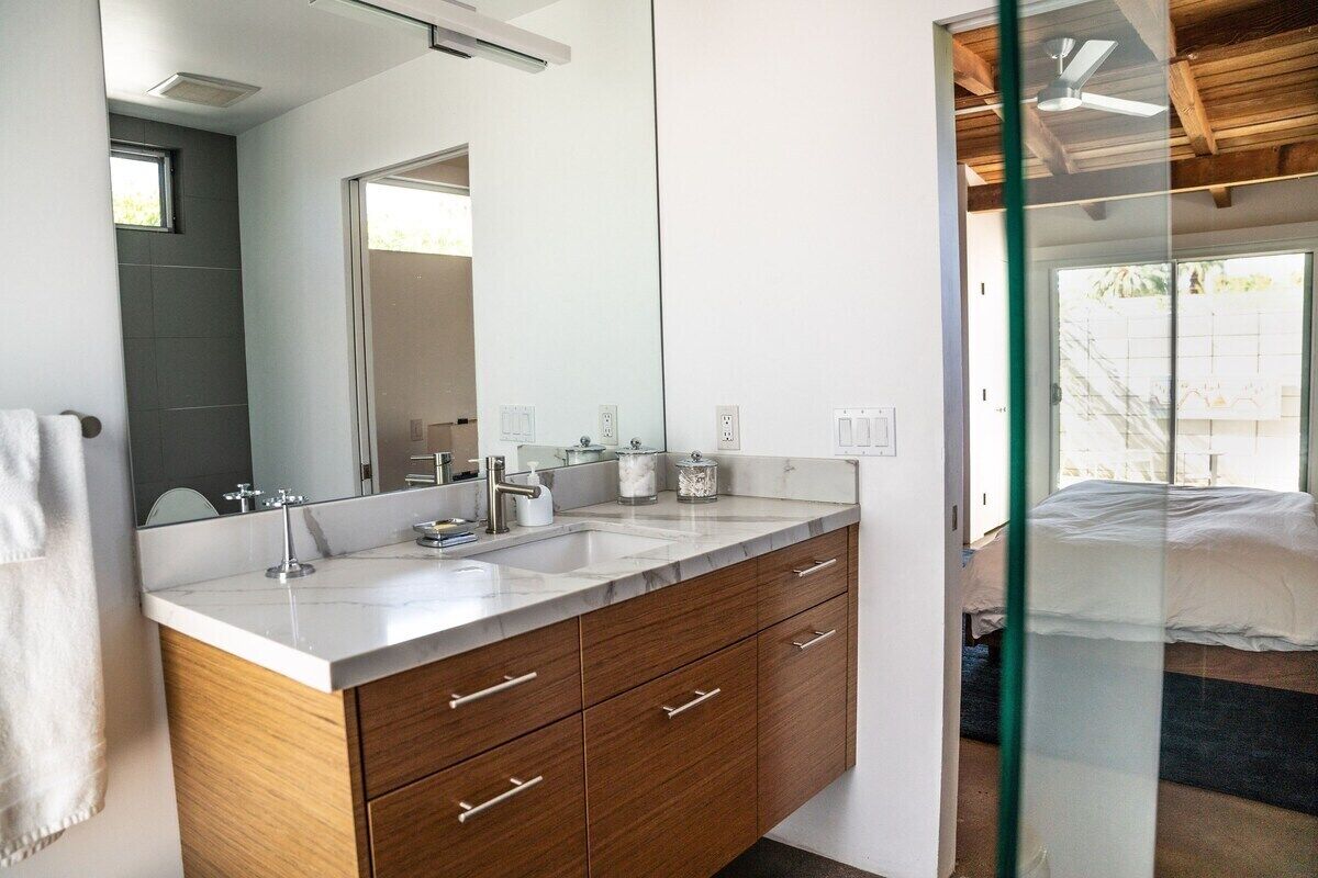 A modern bathroom with a large mirror, two sinks, and wooden cabinets.
