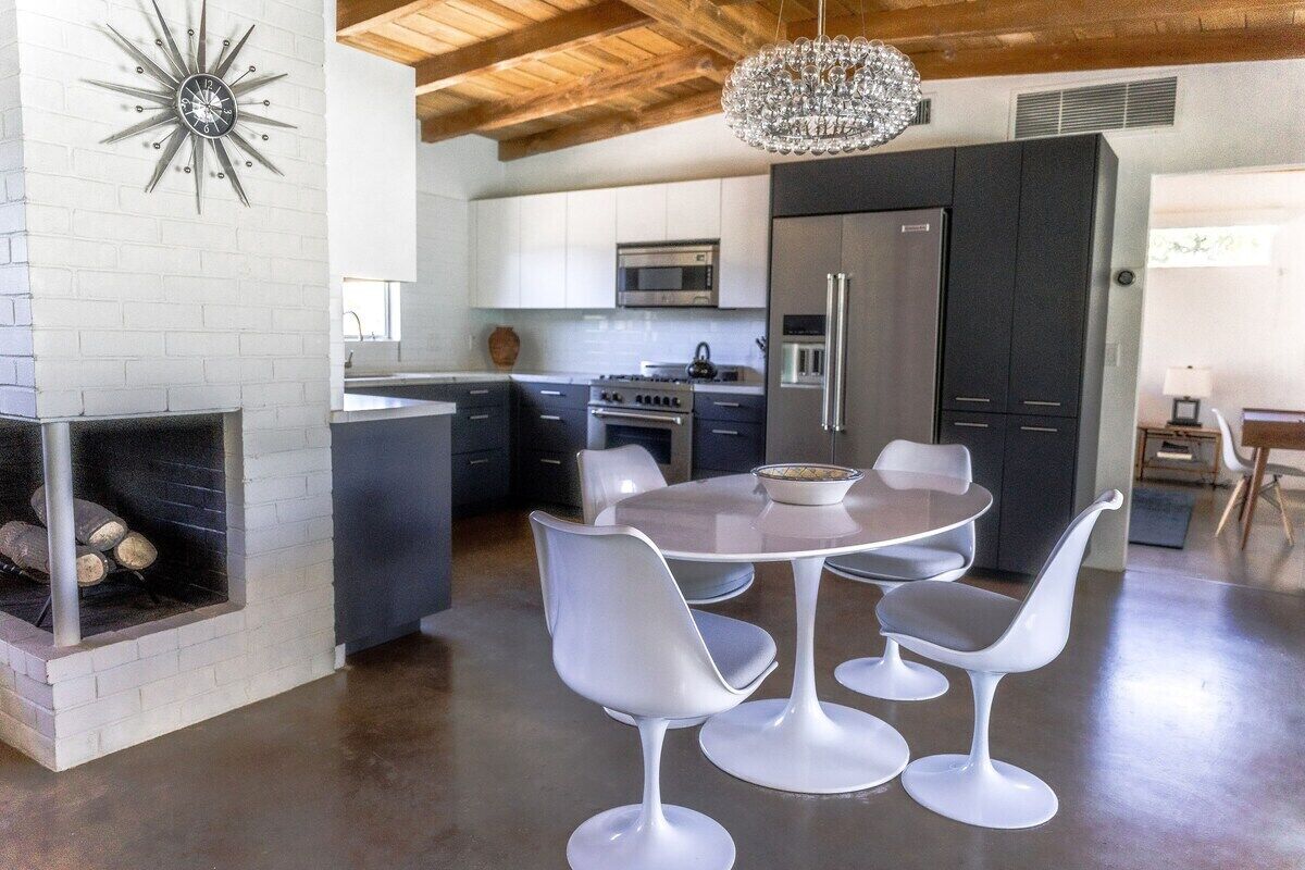 Una cocina moderna con armarios blancos, una isla central, estufa integrada y un refrigerador de acero inoxidable.