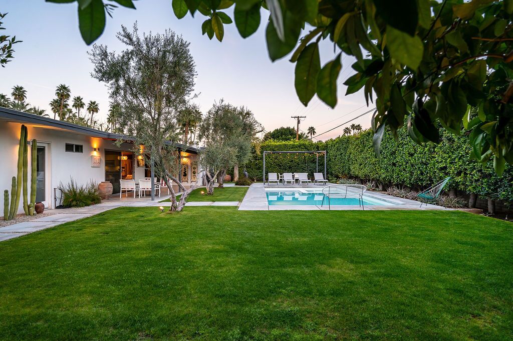 A modern house with a swimming pool, a patio with outdoor furniture, and a well-maintained lawn.
