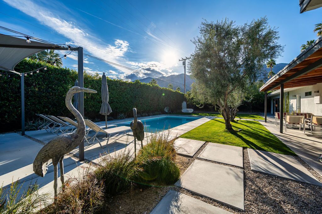 A backyard with a swimming pool, outdoor seating, and decorative sculptures.