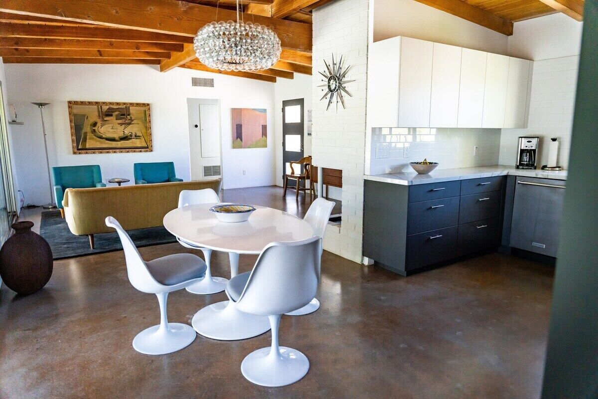 A modern kitchen with white cabinets, a dark countertop, and a coffee machine.