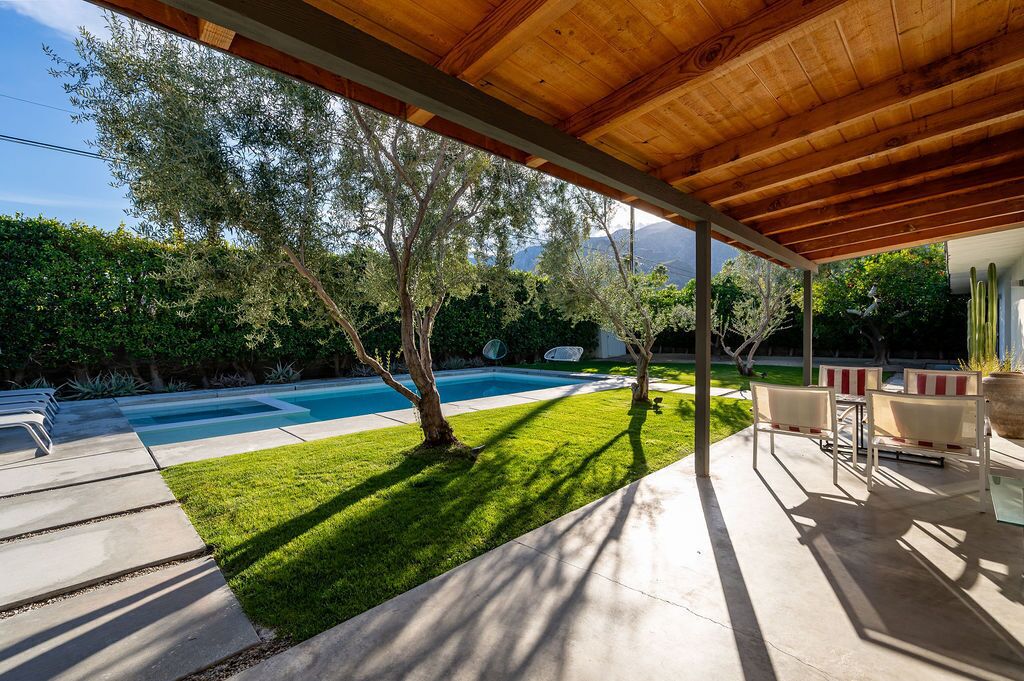 A covered patio area with a pool, outdoor furniture, and a view of a mountainous landscape.