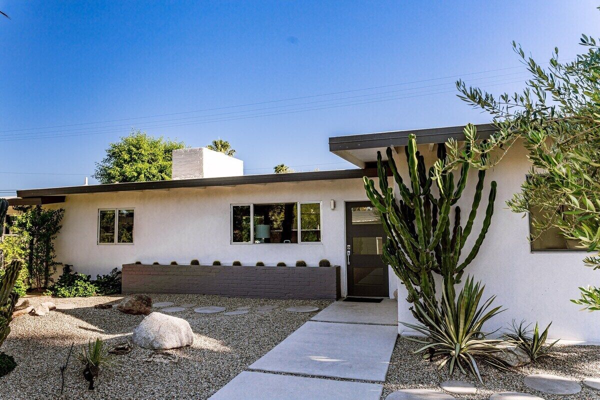 A modern house with a flat roof, a small front porch, and a cactus garden.