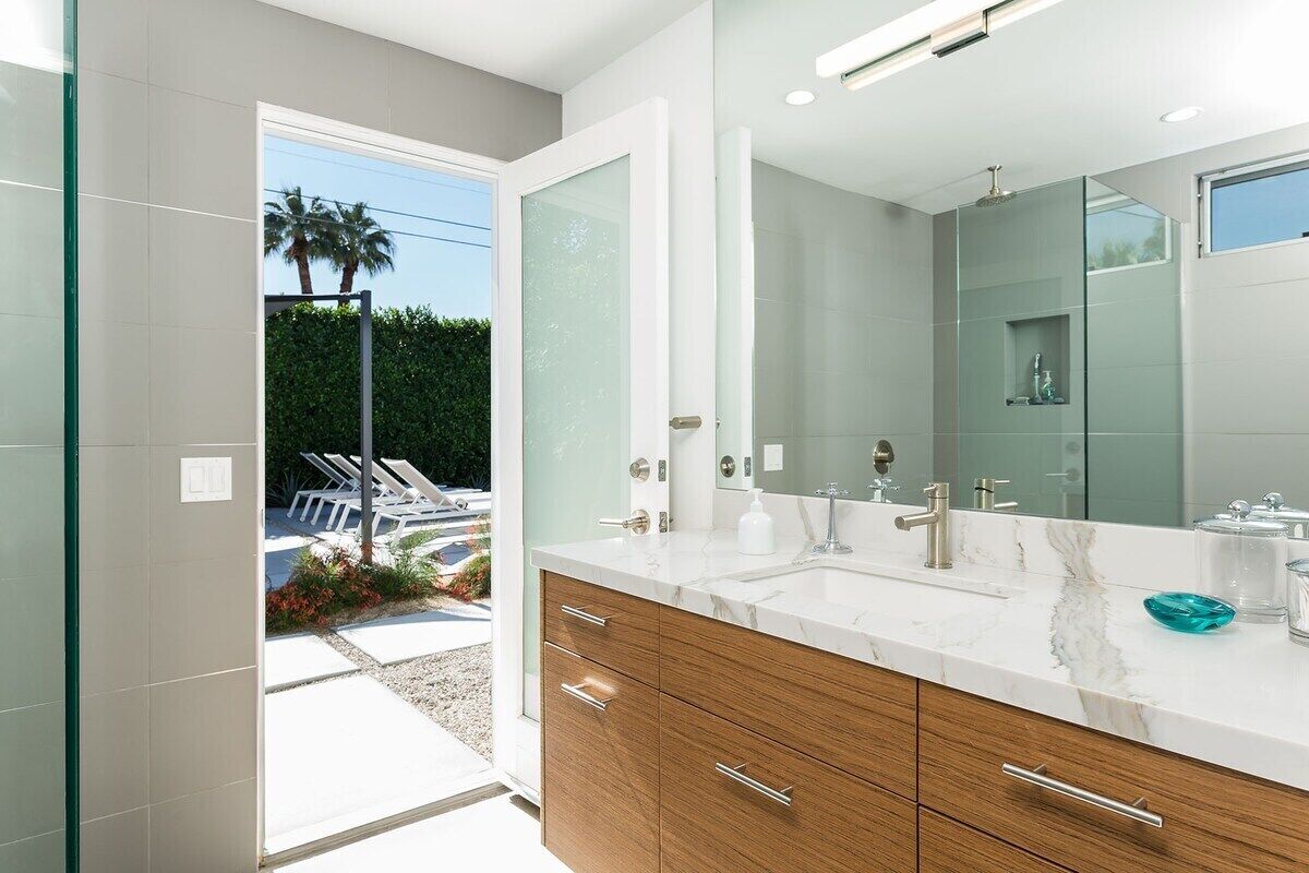 A modern bathroom with a large mirror, dual sinks, and wooden cabinetry.