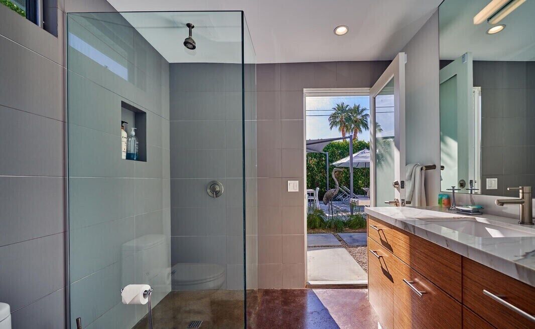 Un baño moderno con ducha vidriada, tocador con espejo y vistas al exterior.